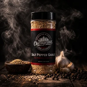 Chicageaux Salt Pepper Garlic Seasoning jar surrounded by smoke, garlic, and peppercorns